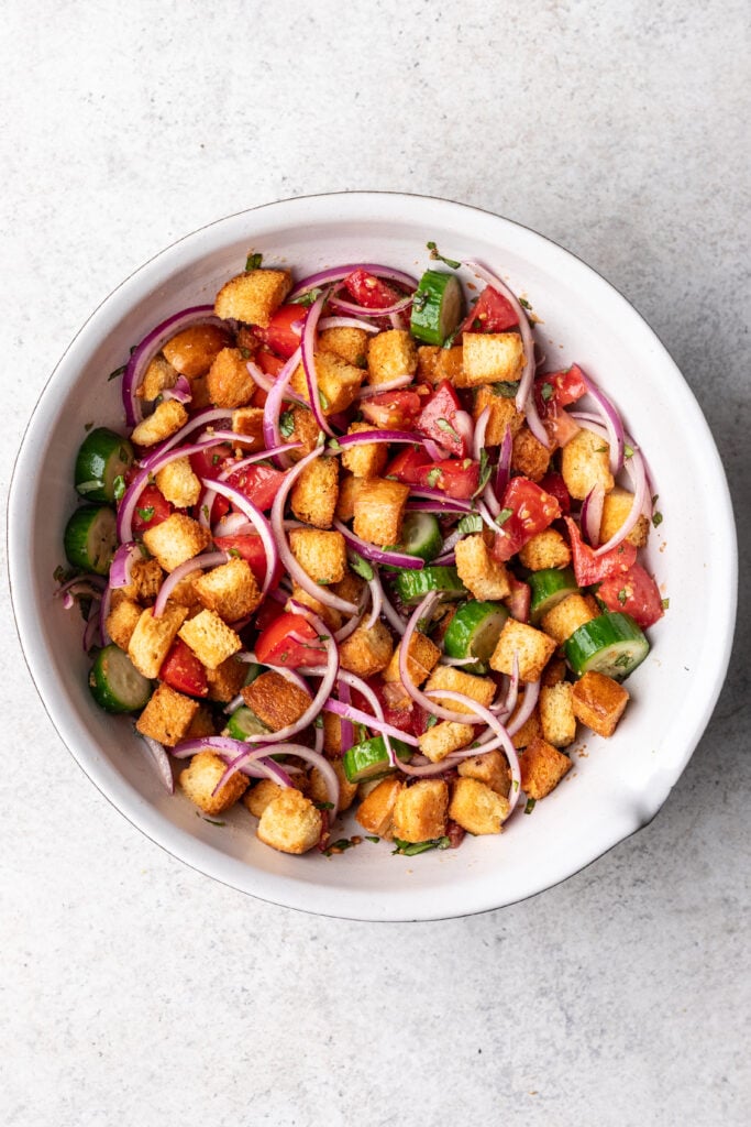 tomatoes, cucumber, red onion and croutons in a bowl