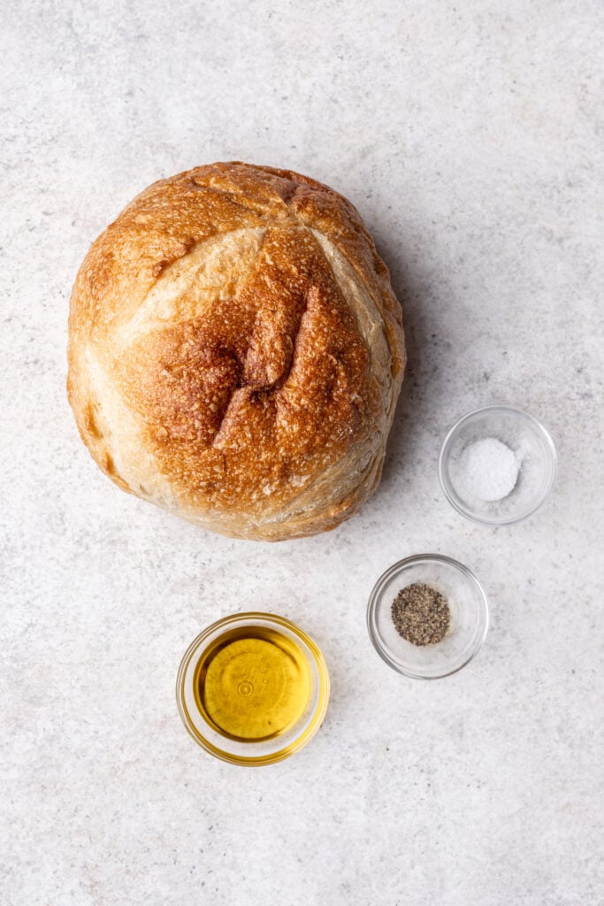 sourdough, oil, salt and pepper on a grey board