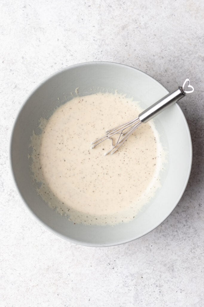 caesar dressing in a bowl with a whisk