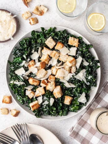 kale caesar salad in a bowl with croutons and cheese on top