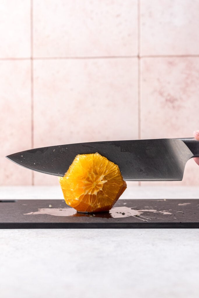 knife cutting an orange on a cutting board