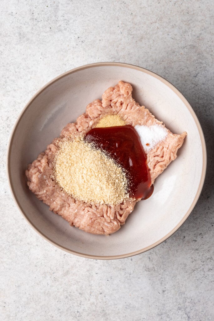 raw chicken in a bowl with breadcrumbs, bbq and spices