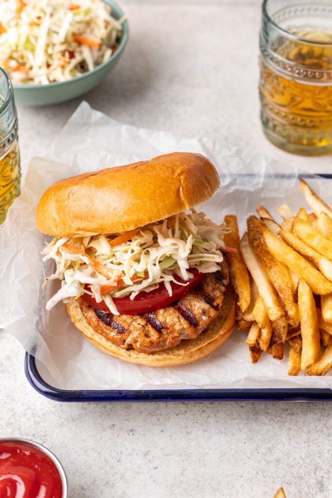 grilled bbq chicken burger with coleslaw and fries on the side