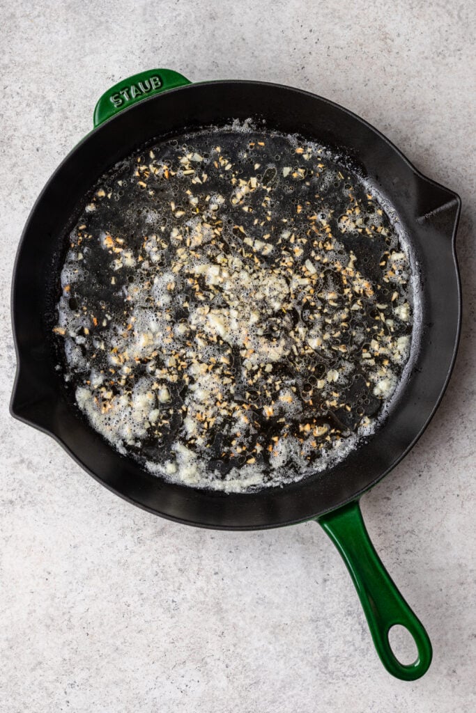 shallots and garlic cooking in a cast iron skillet