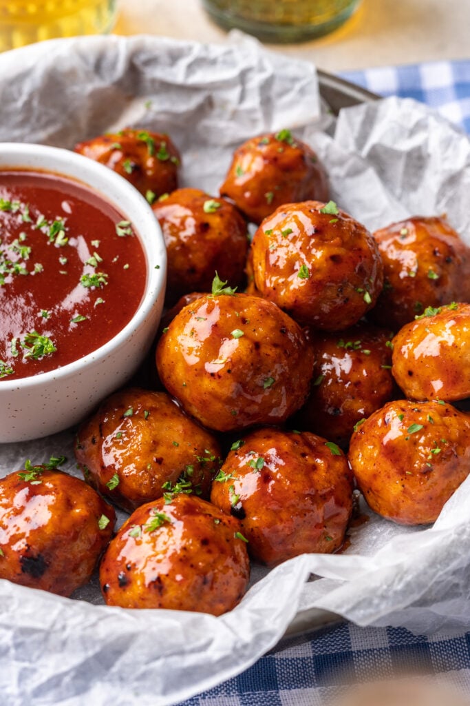 bbq meatballs on a plate with extra bbq sauce on the side
