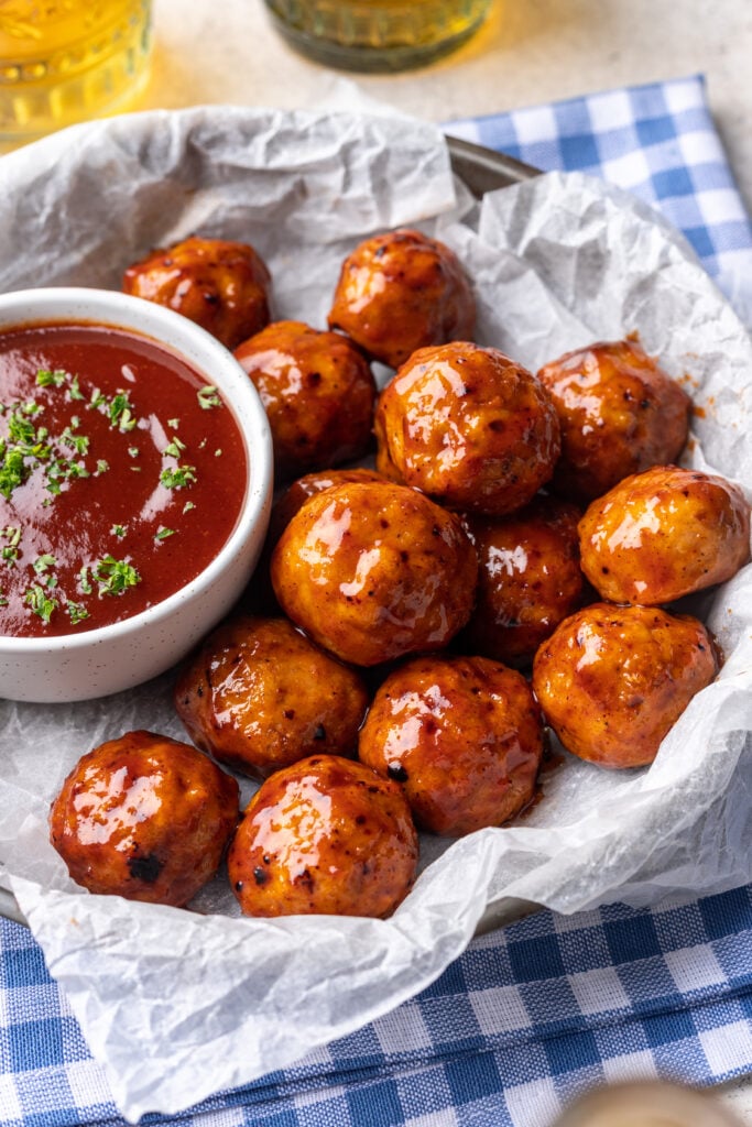 bbq meatballs on a plate with extra bbq sauce on the side