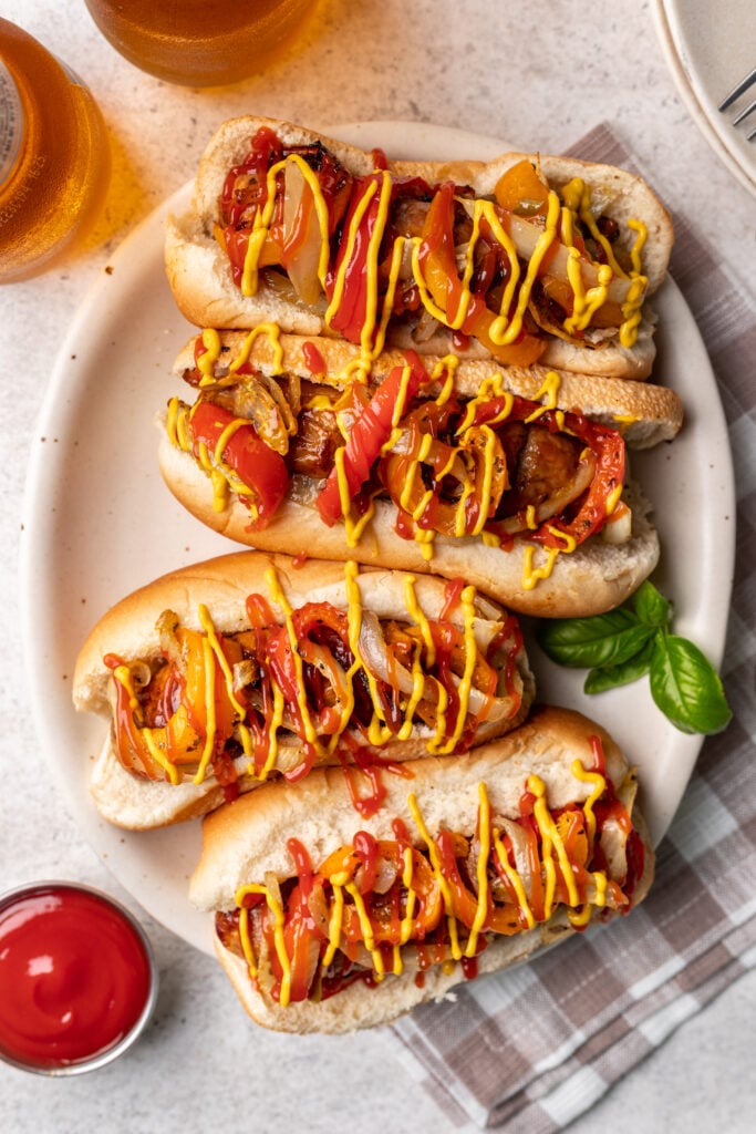 hot dog bun with sausage, peppers and onions drizzled with mustard and ketchup