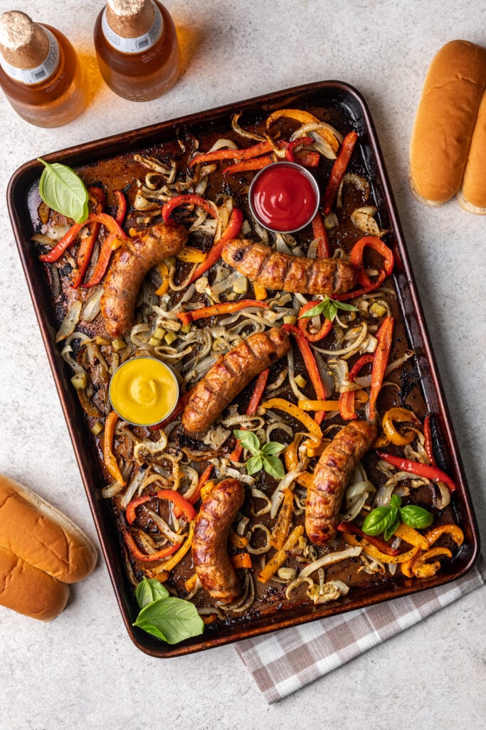onions, peppers and sausages on a sheet pan