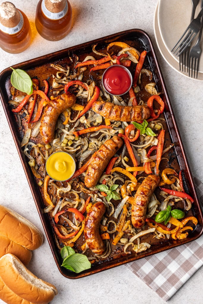 onions, peppers and sausages on a sheet pan