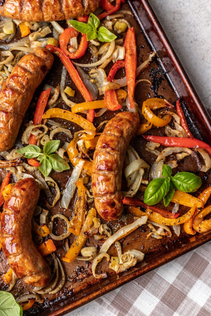 cooked sausage on a sheet pan with onions and peppers