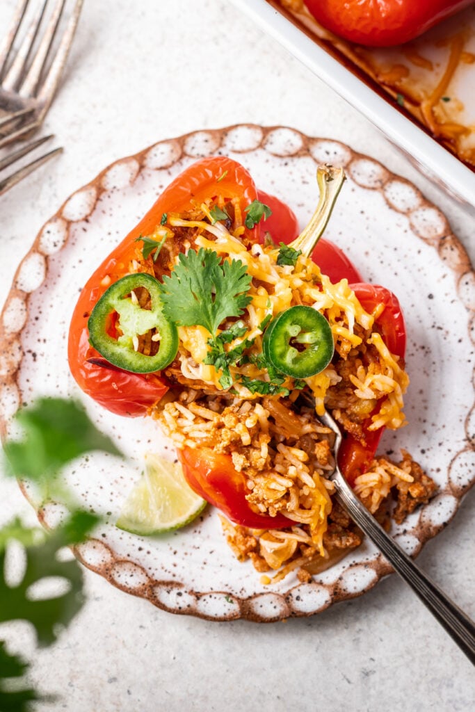 a stuffed bell pepper with ground turkey and rice on a white plate with a bite taken out of it