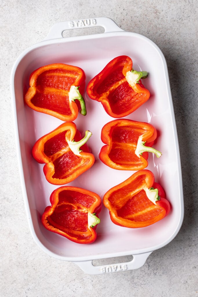 red bell peppers cut in half in a white dish