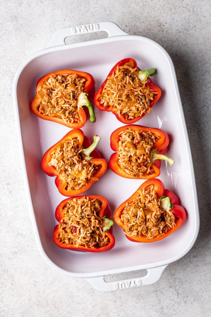 red bell peppers cut in half in a white dish with ground turkey filling