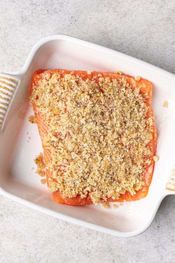 panko breadcrumbs on a piece of salmon in a white baking dish