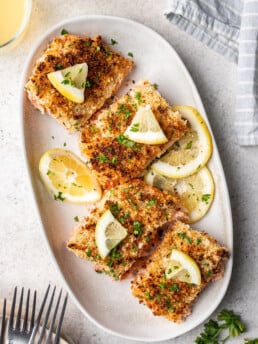 sliced panko crusted salmon on a white oval platter with lemon slices