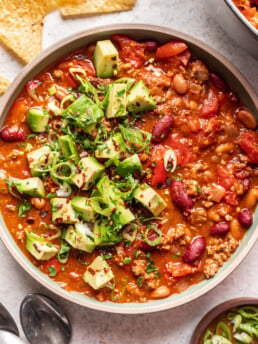 a bowl of ground beef chili with avocado and green onions