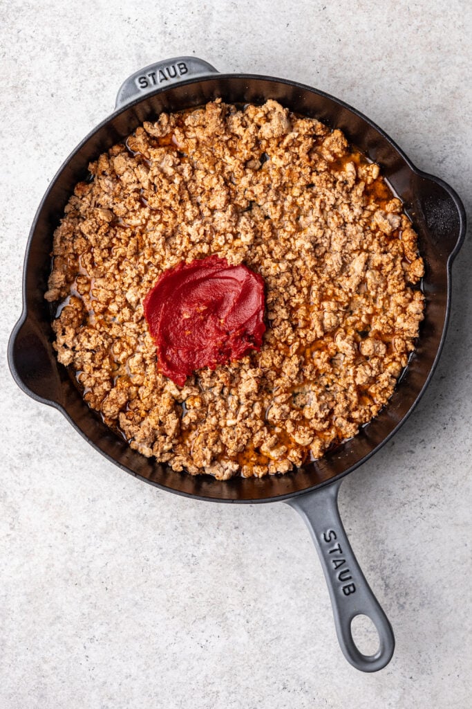 ground meat in a skillet with spices and tomato paste