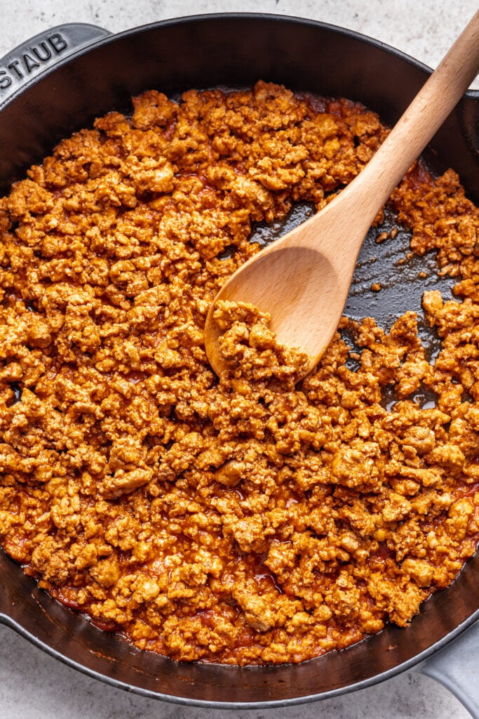 ground meat in a skillet with a wooden spoon