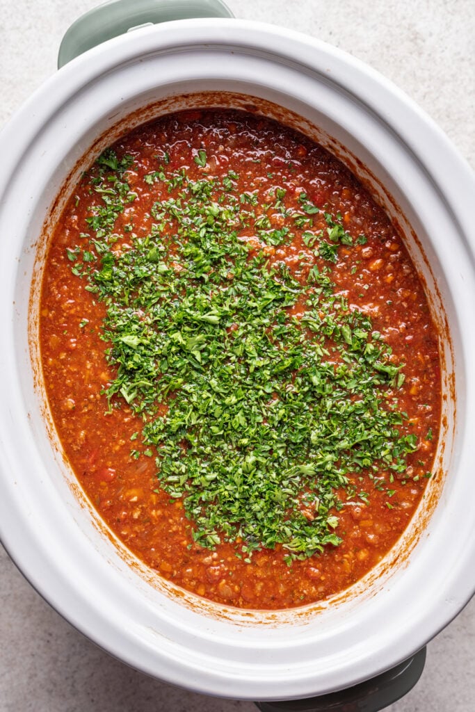 fresh parsley on bolognese sauce in a slow cooker