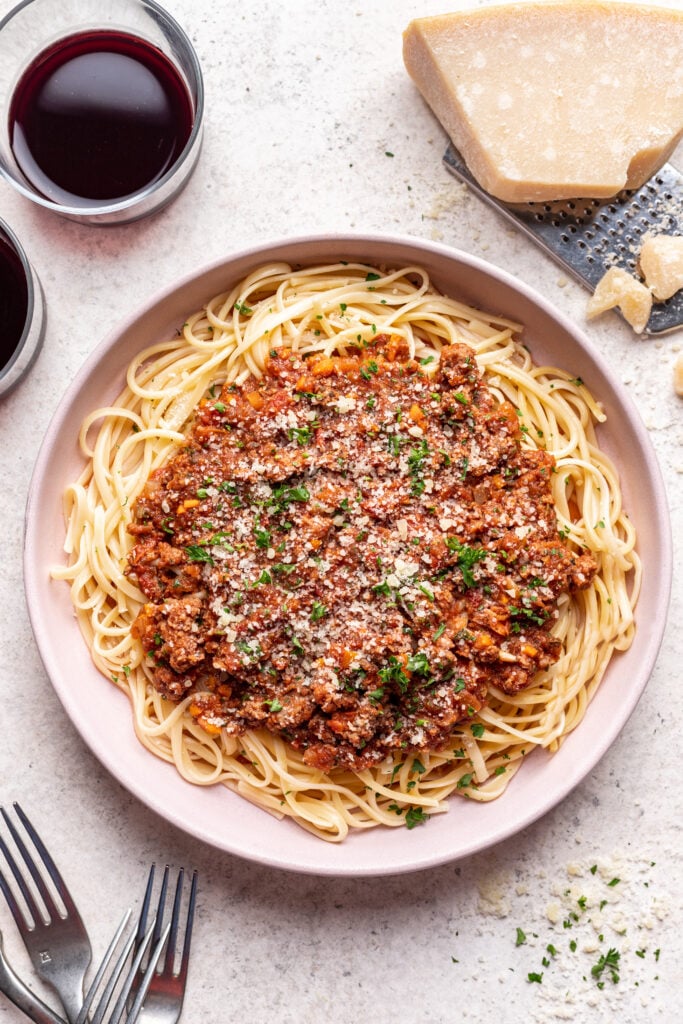 bolognese sauce on a pink plate served over spaghetti