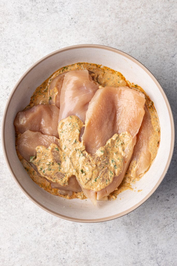 raw chicken in a bowl with yogurt marinade