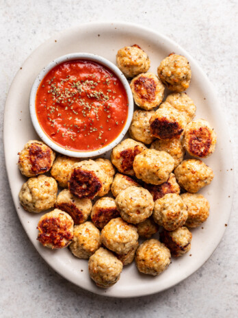 chicken meatballs on a white platter with marinara dipping sauce