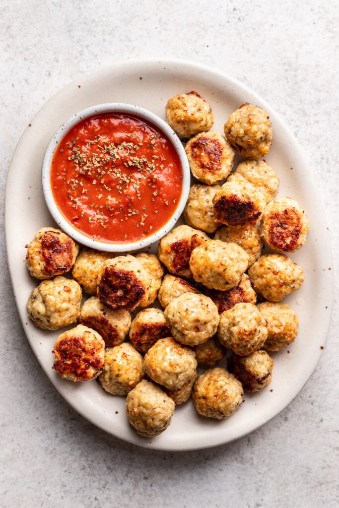 chicken meatballs on a white platter with marinara dipping sauce