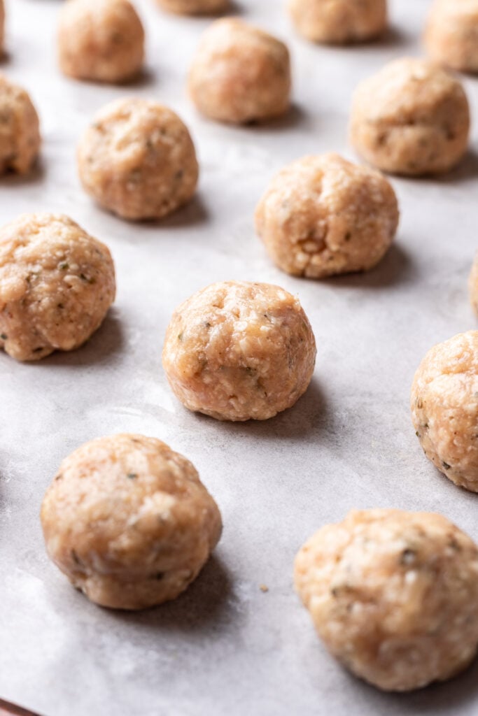 raw chicken meatballs on a sheet pan