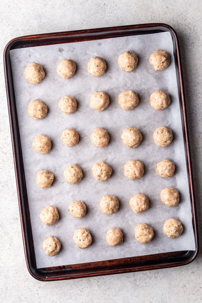raw chicken meatballs on a pan