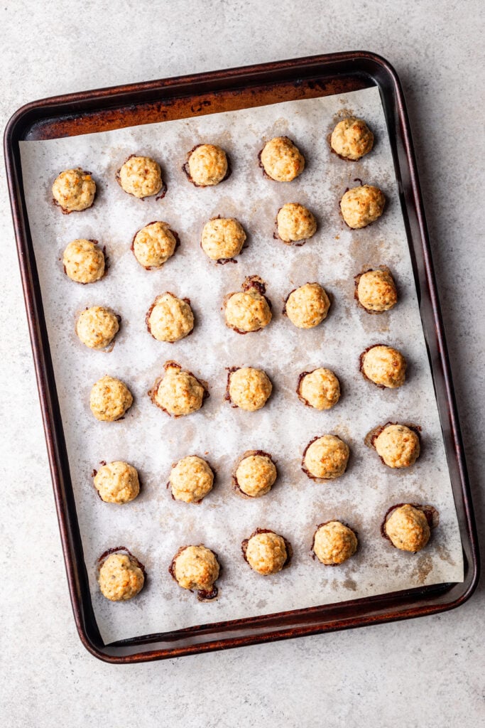 baked chicken meatballs on a sheet pan with parchment paper