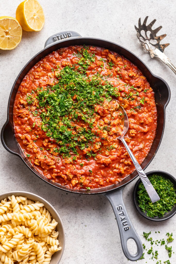 ground chicken bolognese sauce in a skillet with chopped parsley