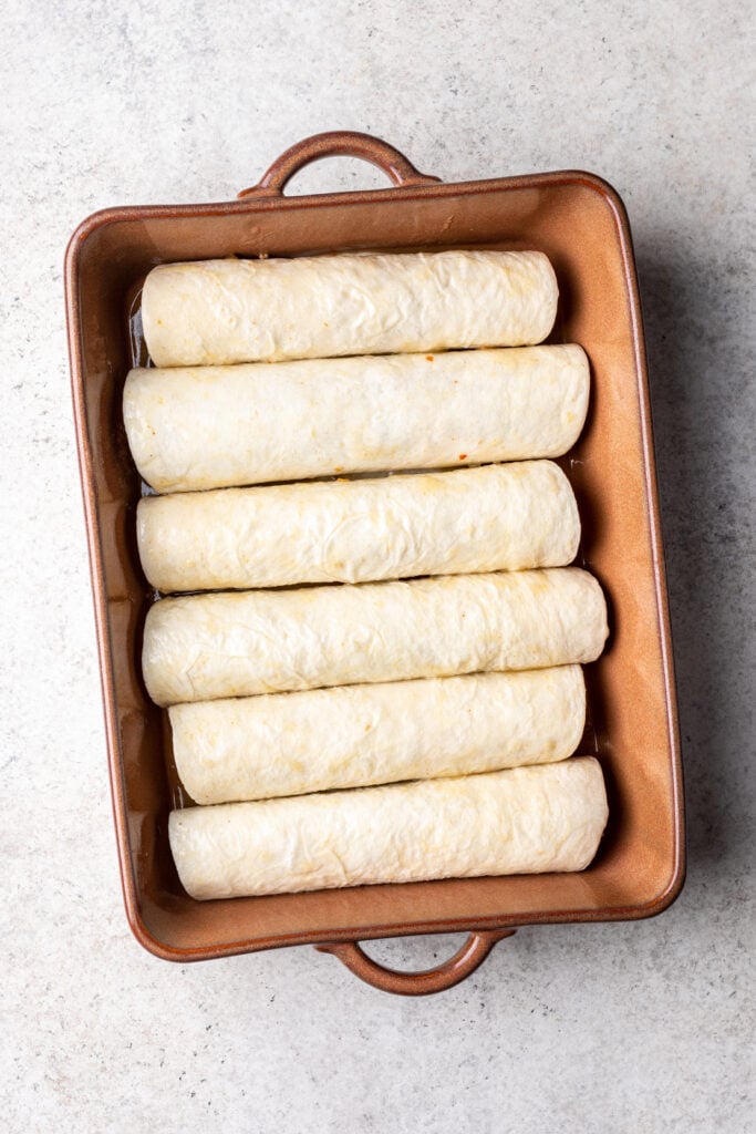 6 tortillas rolled up next to each other in a baking dish