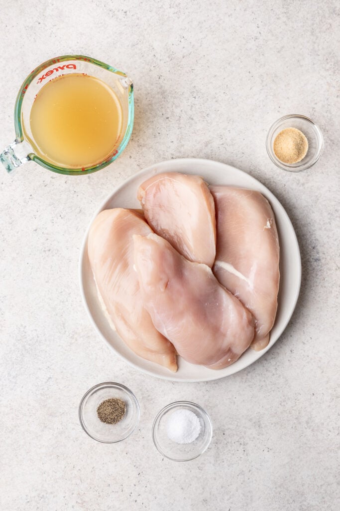 raw chicken on a plate with bowls of additional ingredients