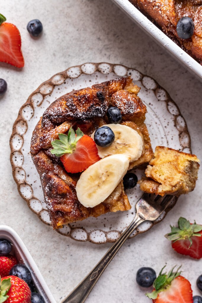 a slice of banana cinnamon french toast with banana and strawberries on top