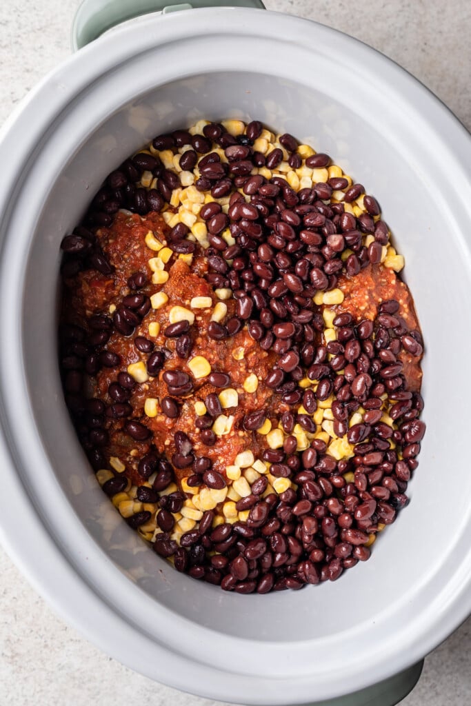 raw chicken, beans, corn and salsa in a slow cooker