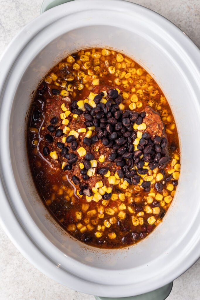 cooked chicken, beans, corn and salsa in a slow cooker