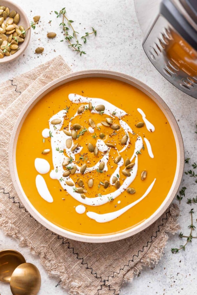 butternut squash soup in a bowl with creme fresh drizzle and pumpkin seeds