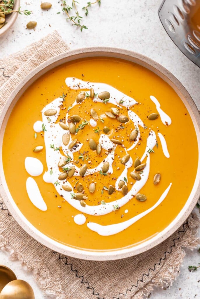 butternut squash soup in a bowl with creme fresh drizzle and pumpkin seeds
