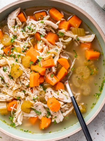 chicken noodle soup with carrots and celery and a spoon