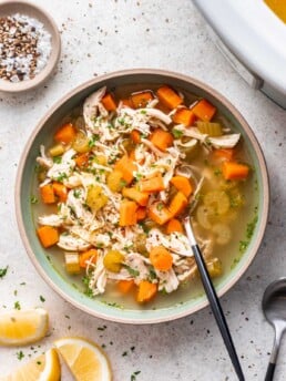 chicken noodle soup with carrots and celery and a spoon