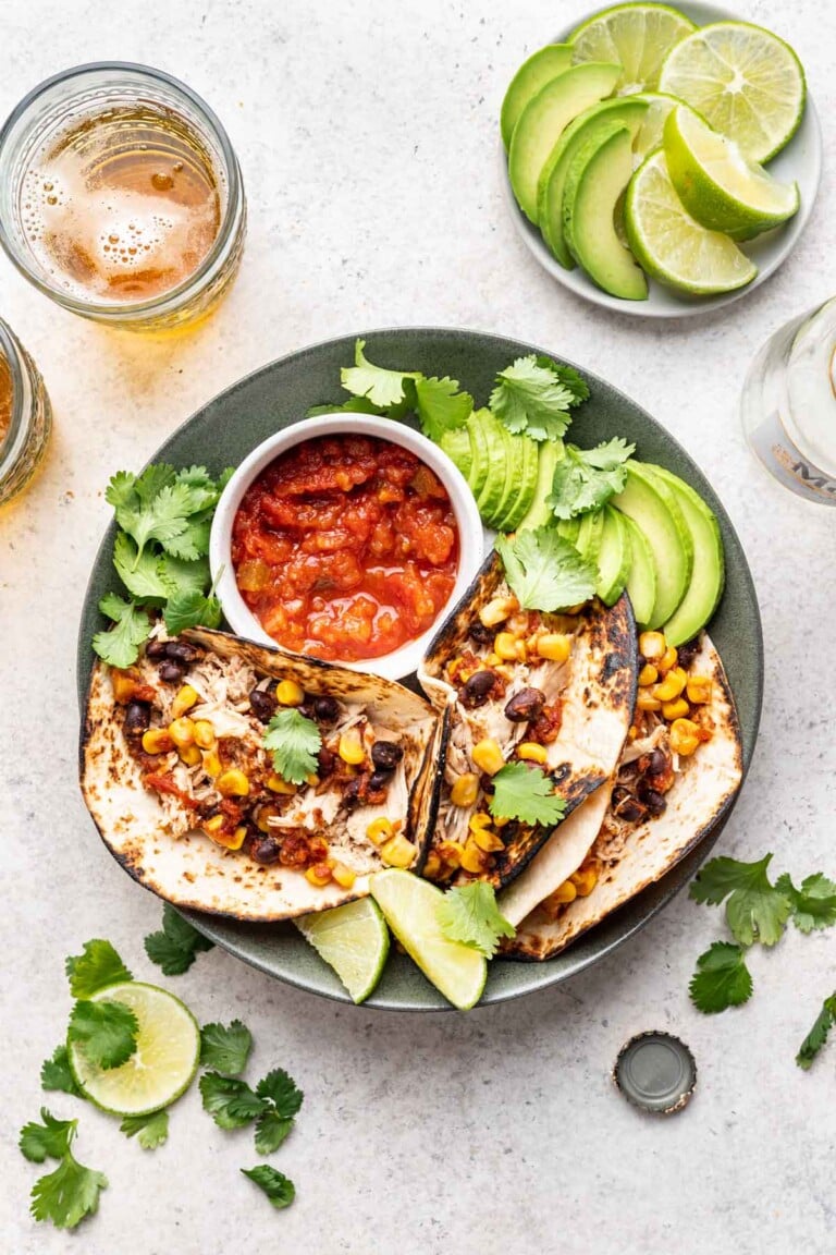 shredded chicken tacos on a plate with salsa and avocado
