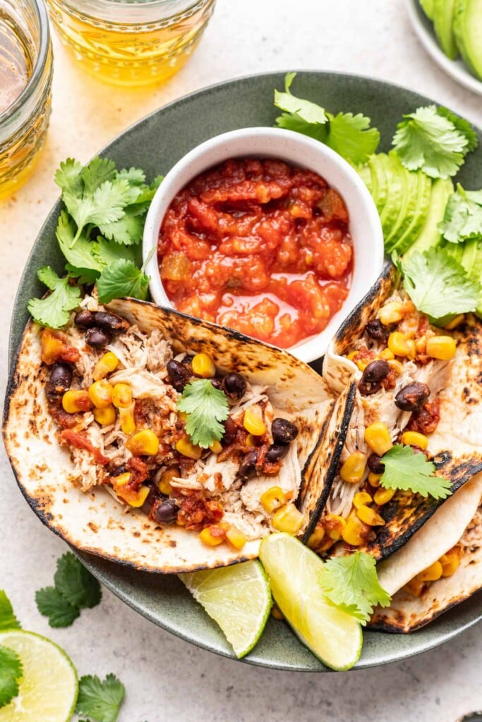 shredded chicken tacos on a plate with salsa and avocado