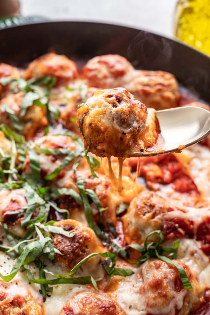 a spoon holding a cheesy meatball