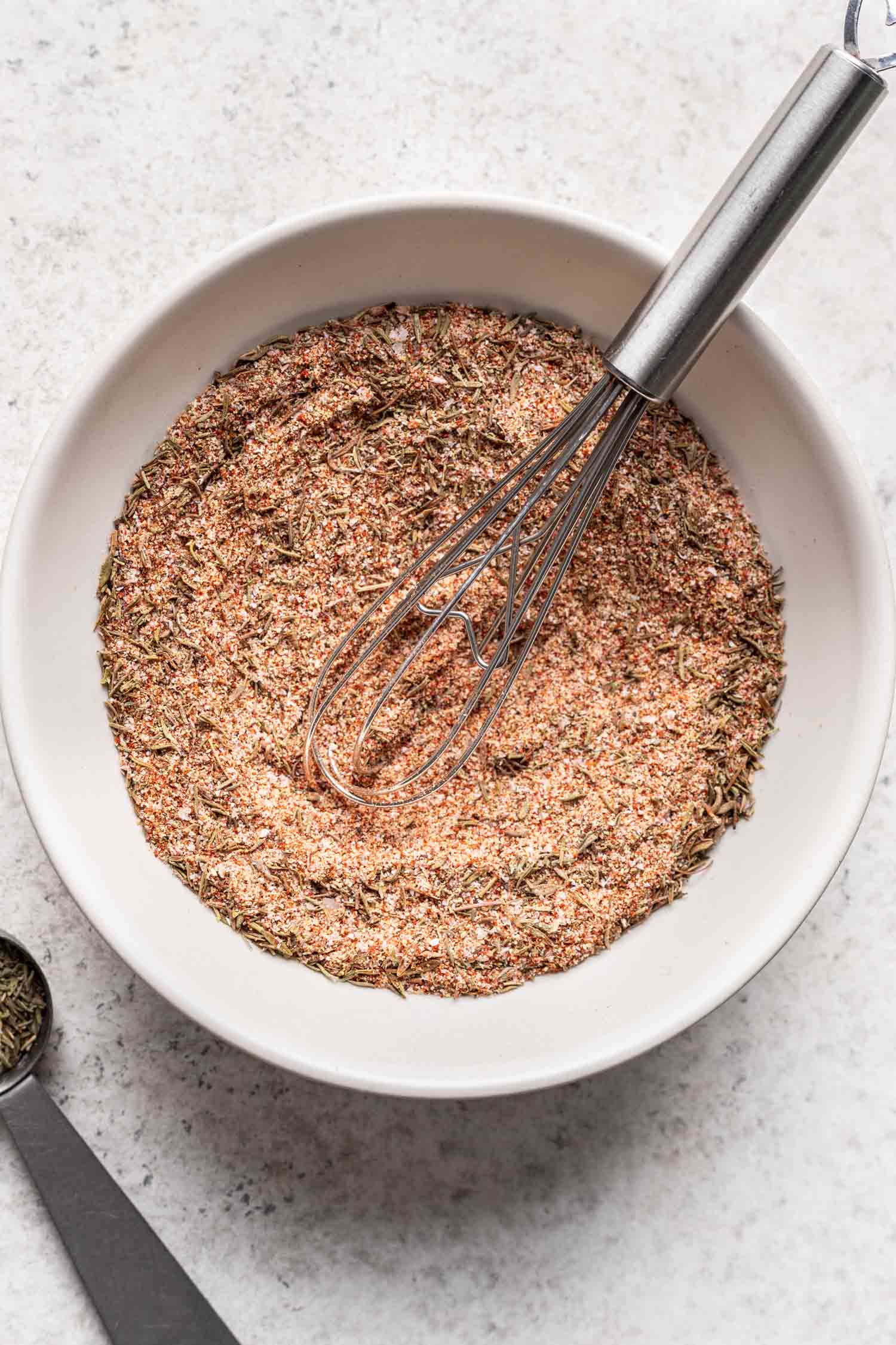 a white bowl with spices and a whisk