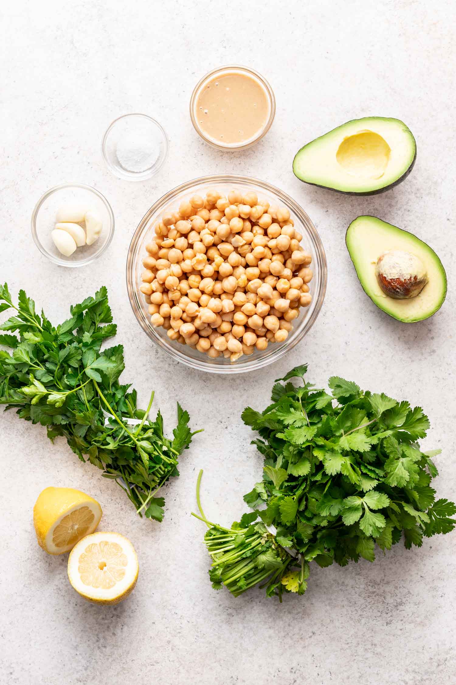 ingredients in bowls on a grey background. Chickpeas, parsley and avocado