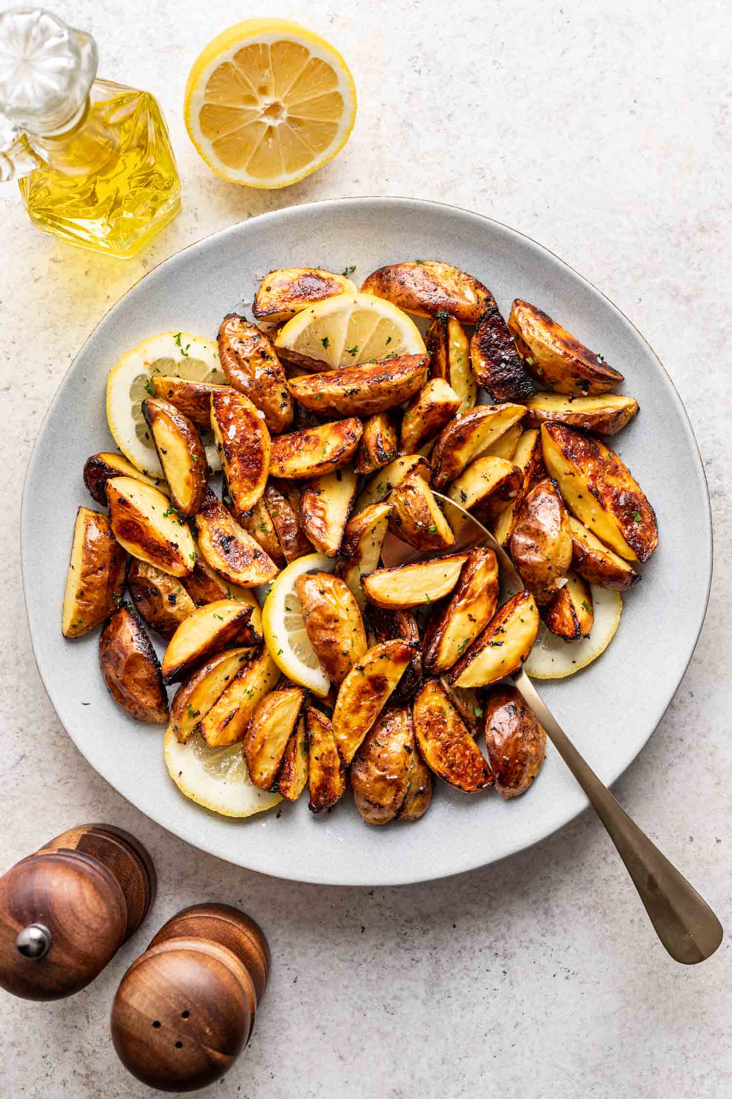roasted potatoes in a white bowl with a serving spoon
