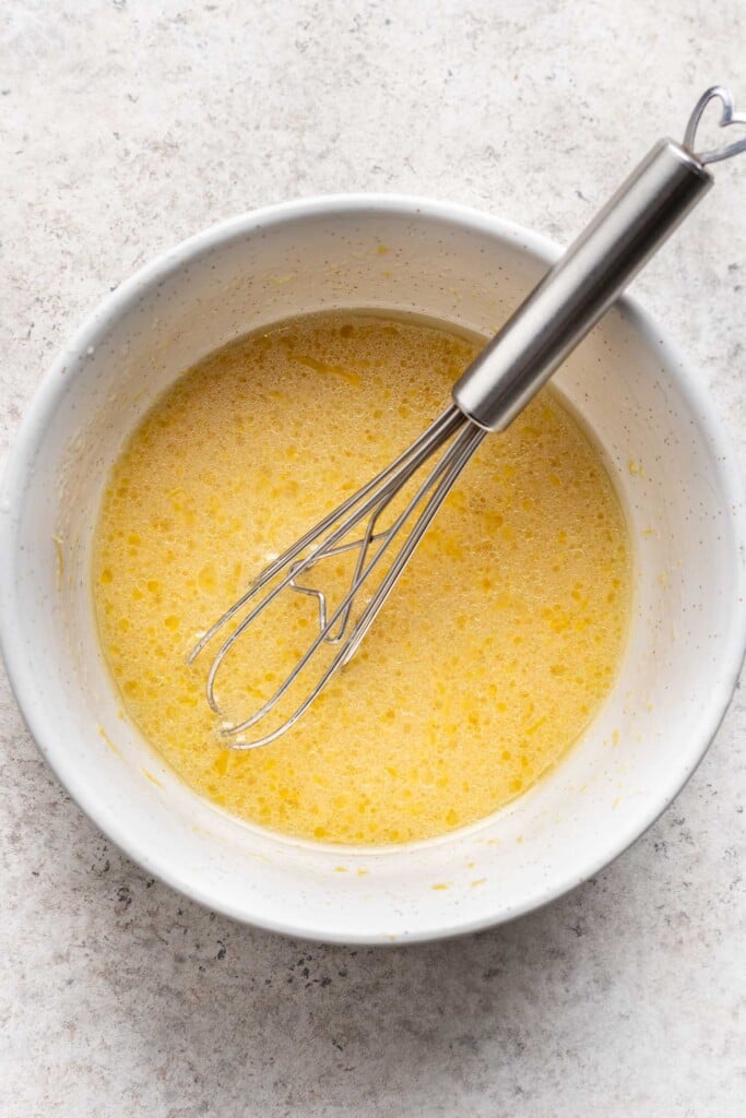 a bowl of dressing with a whisk