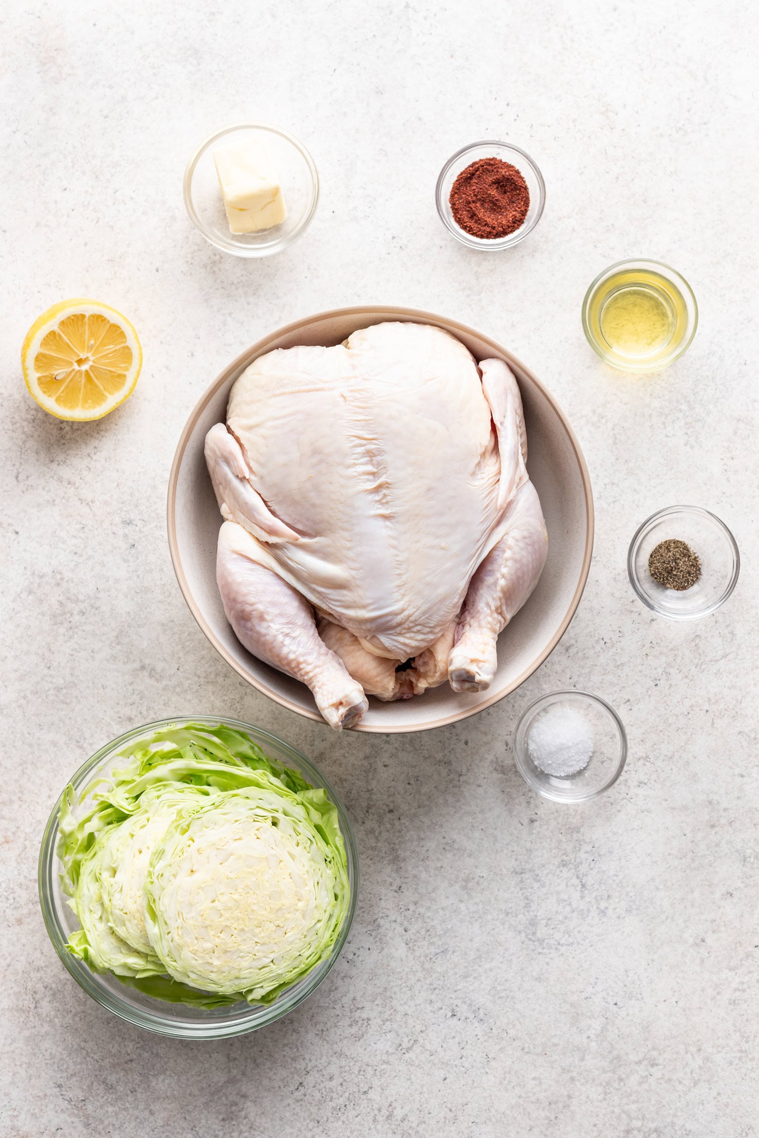 bowls of ingredients like a whole chicken, cabbage, spices and lemon
