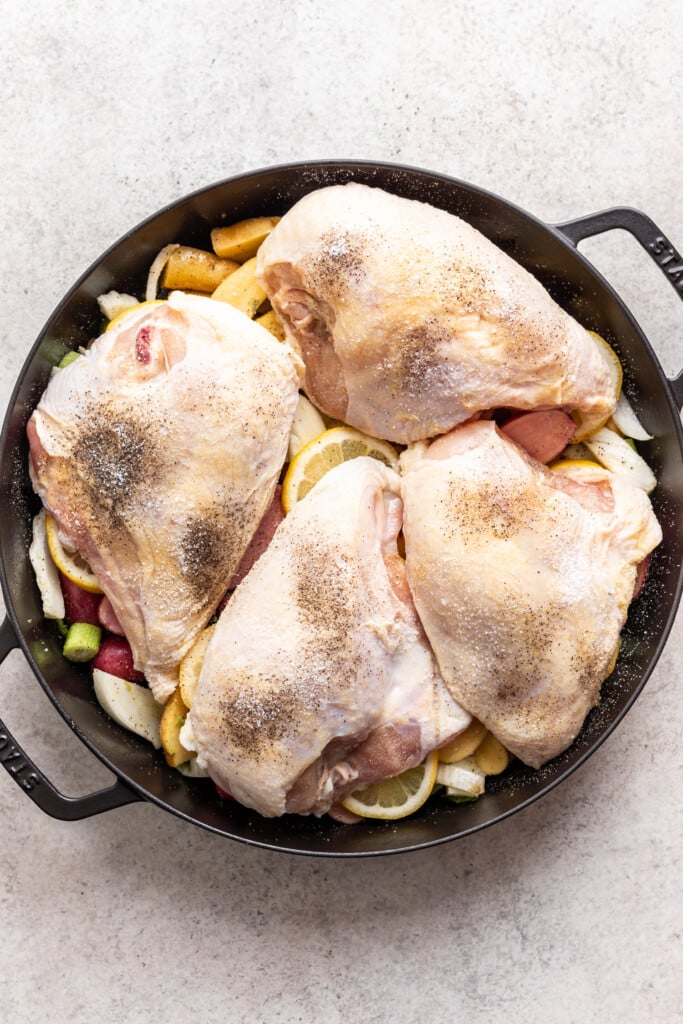 raw chicken pieces in a cast iron pan