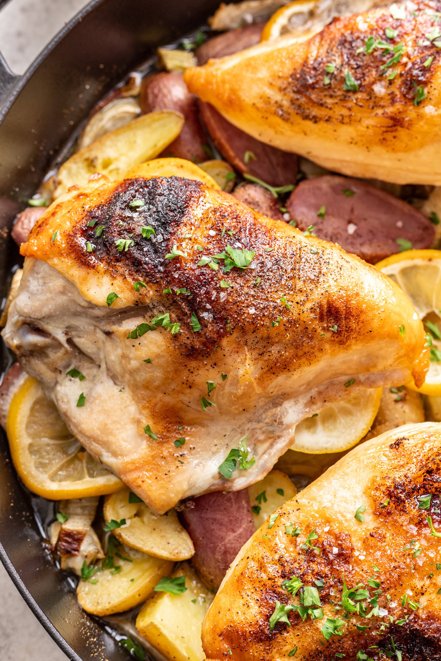 cooked chicken breast over potatoes and lemon